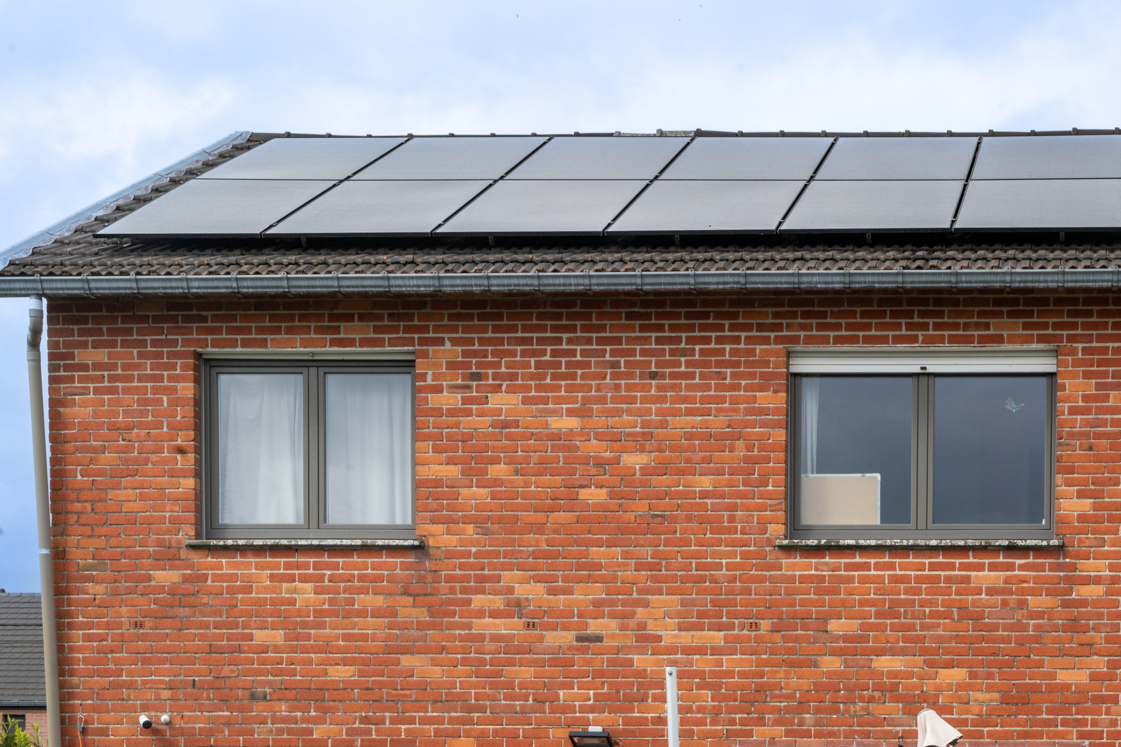 Facade en briques avec panneaux solaires en toiture.
