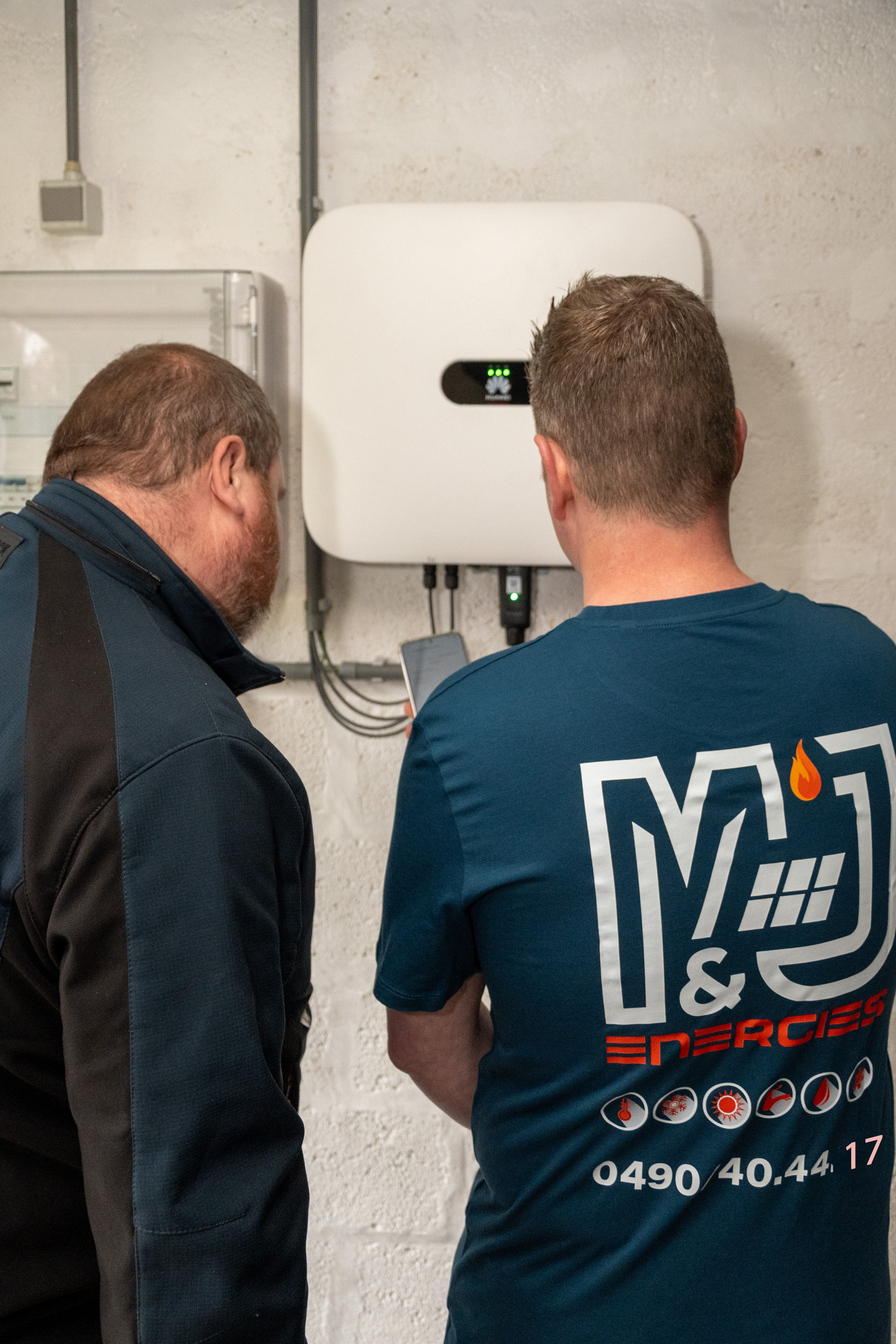 Deux techniciens devant un onduleur photovoltaique.